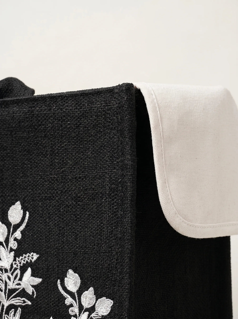 Close-up of white botanical floral embroidery on black jute tote bag artisan canvas bag for women WestStyle Pakistan