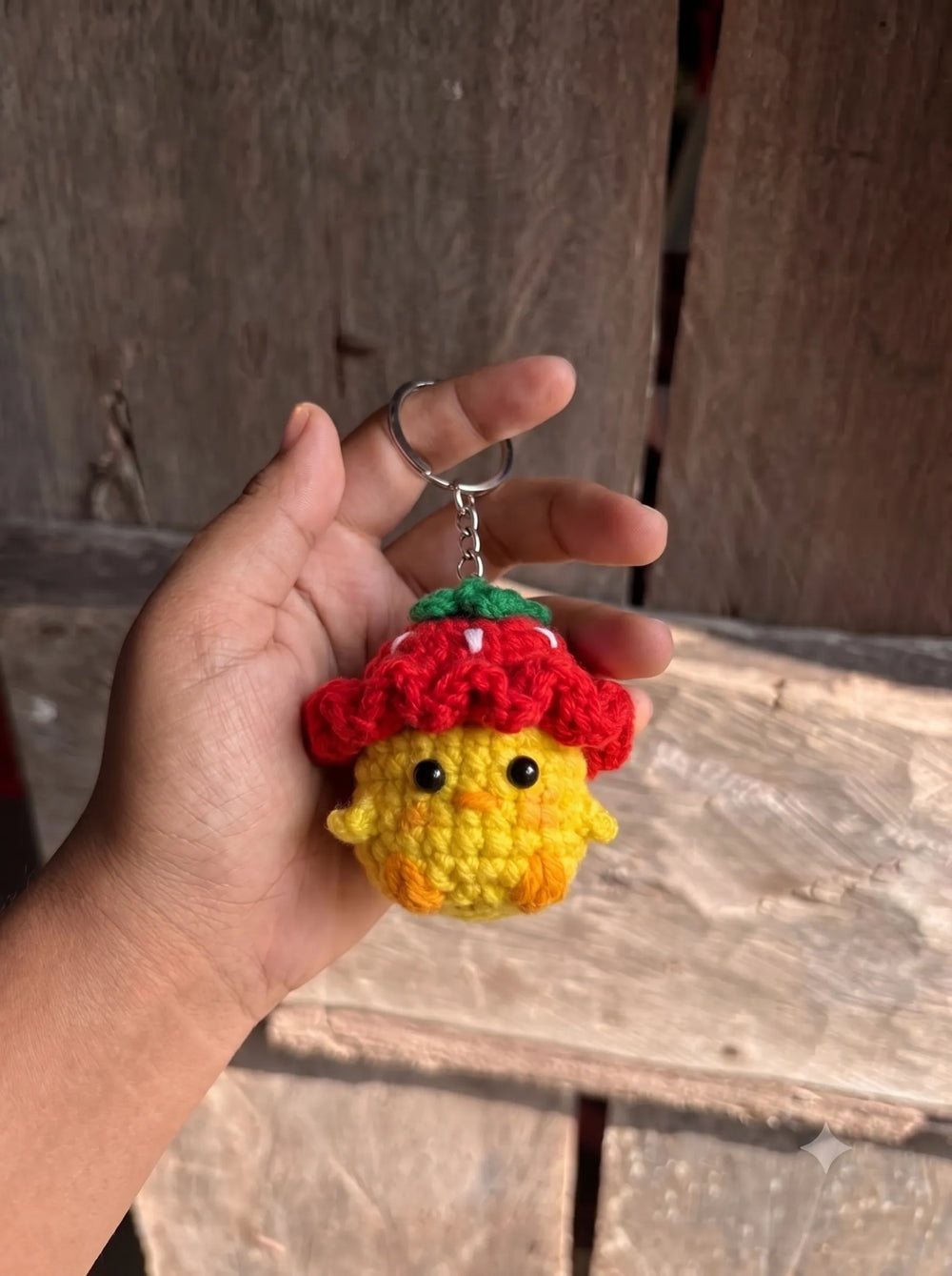 Close-up of handmade crochet baby chick keychain showing black bead eyes, orange beak and red strawberry hat - WestStyle Pakistan