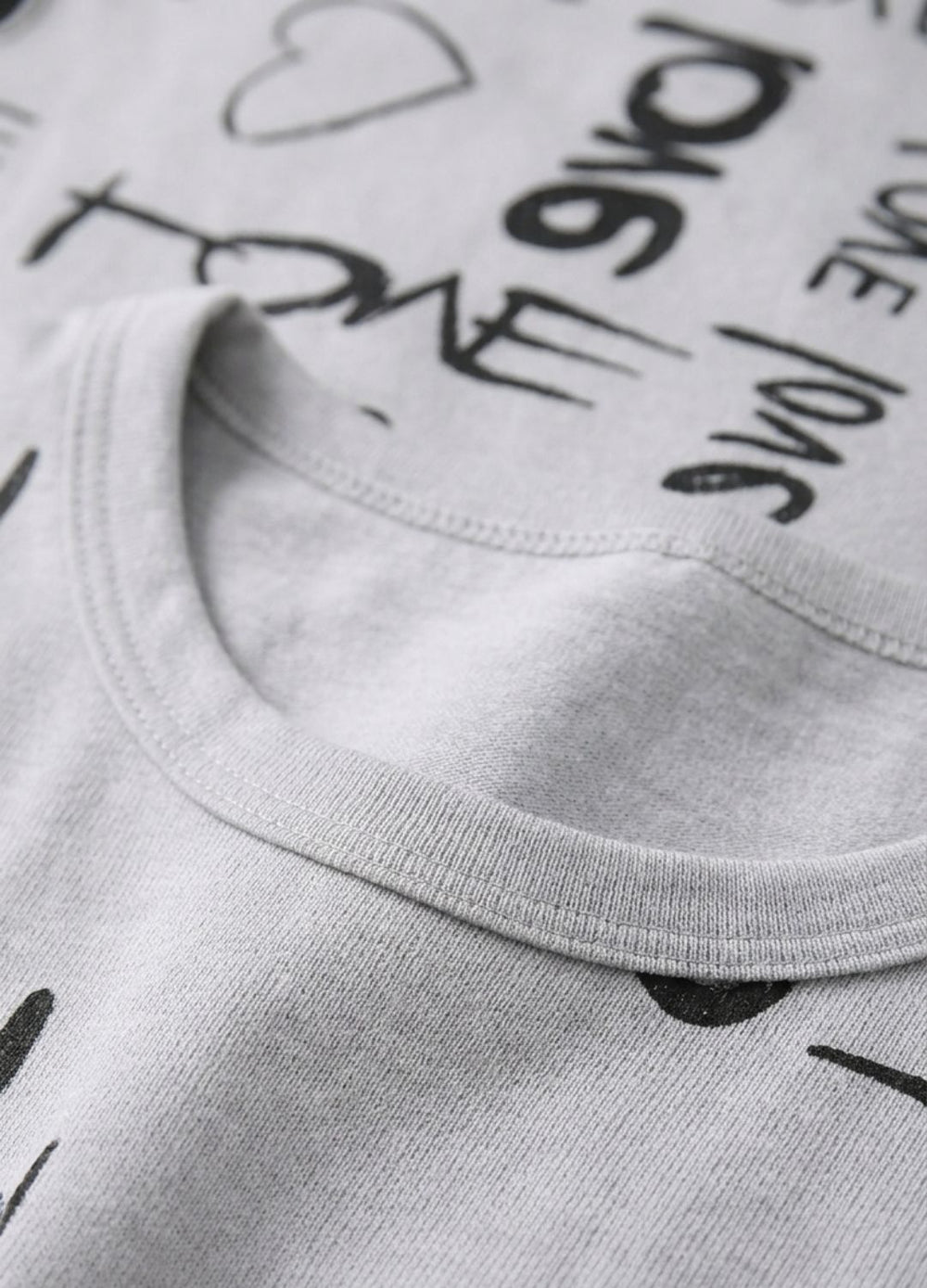 Close-up of a pink shirt with black text and a visible brand label.