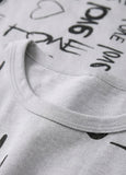 Close-up of a pink shirt with black text and a visible brand label.