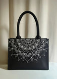Black women handbag with white mandala design on a beige curtain background
