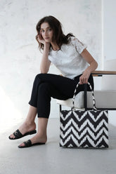 Woman holding a black and white zigzag patterned canvas tote bag in a minimalistic studio - WestStyle