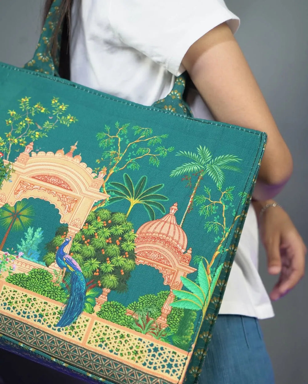 Person holding a green tote bag with a mughal print design of a garden and peacock for women - WestStyle
