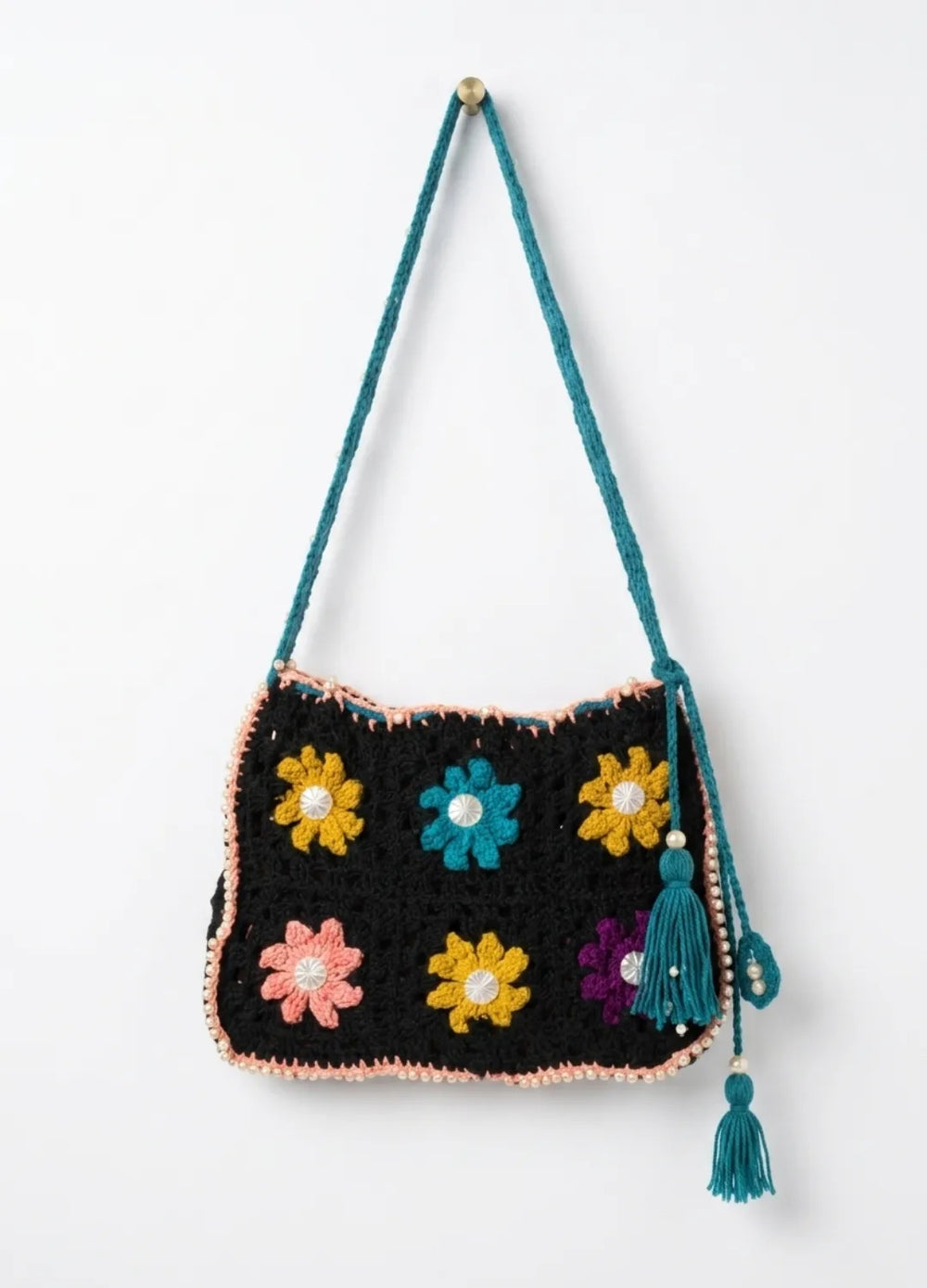 Crocheted bag with colorful flower patterns and tassels on a white background