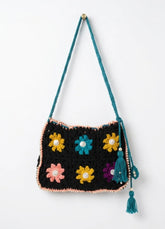 Crocheted bag with colorful flower patterns and tassels on a white background