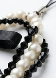 Pearl and black beaded bracelet on a white background