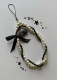 Pearl and black beaded phone strap with a black bow on a light gray background