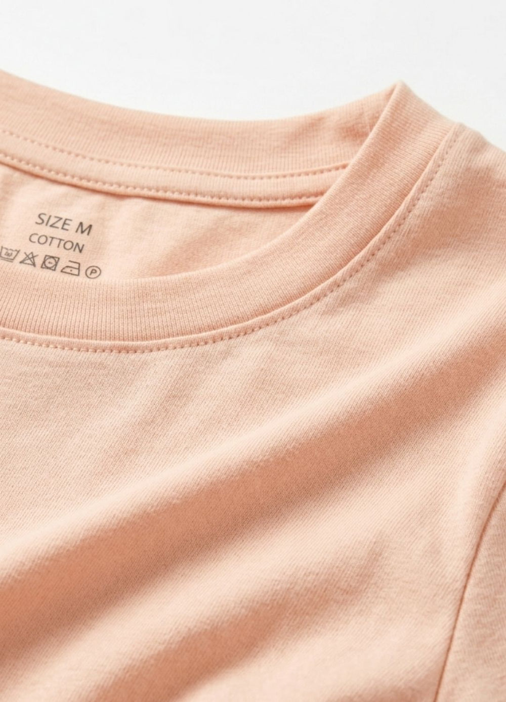 Close-up of a pink t-shirt with size and material labels.