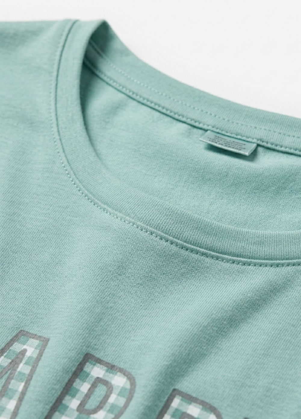 Close-up of a light green t-shirt with text and pixelated design on a white background