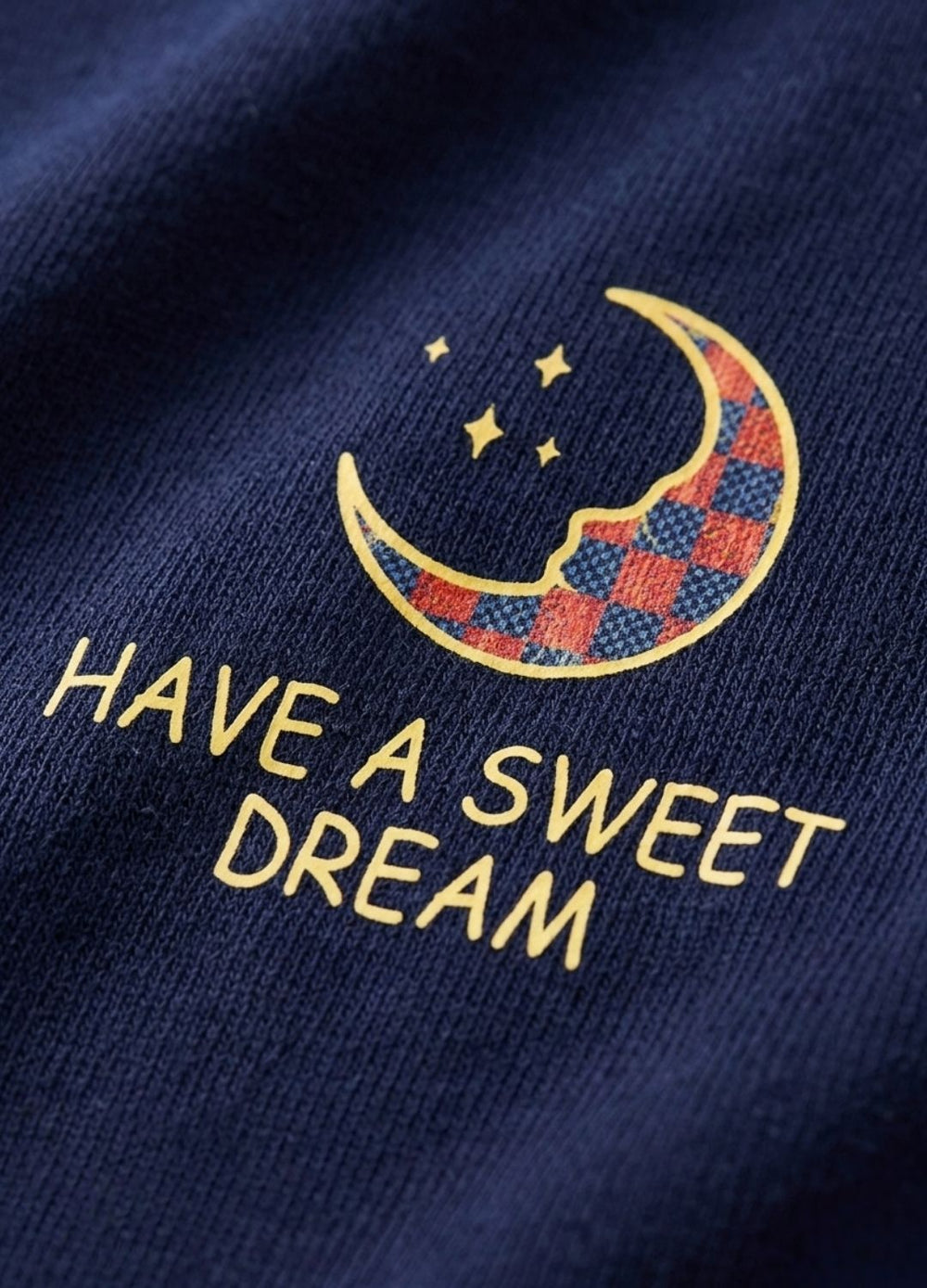 Embroidered design on a dark fabric with 'Have a Sweet Dream' text and moon and stars pattern.
