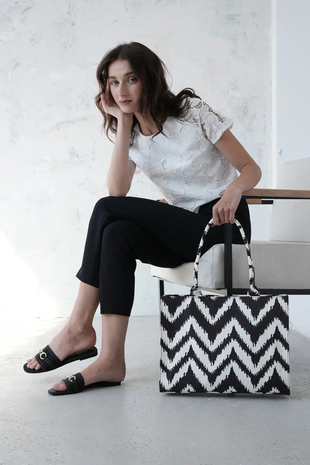 Woman holding a black and white zigzag patterned canvas tote bag in a minimalistic studio - WestStyle