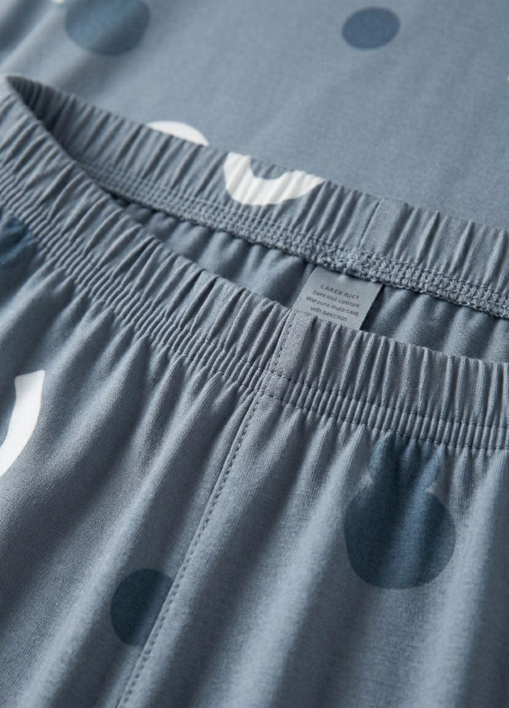 Close-up of blue shorts with a brand label on the waistband.