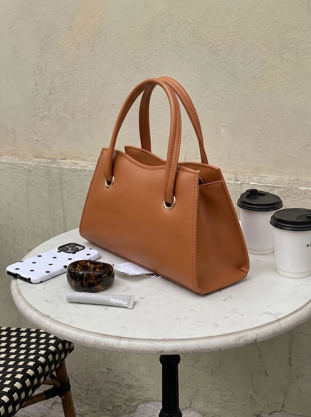 WestStyle Mustard Baul Ring crossbody bag with rounded top handles on a marble café table beside two coffee cups