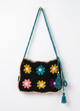 Crocheted bag with colorful flower patterns and tassels on a white background