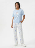 Woman wearing a light blue t-shirt with a bunny design and checkered white pants on a white background