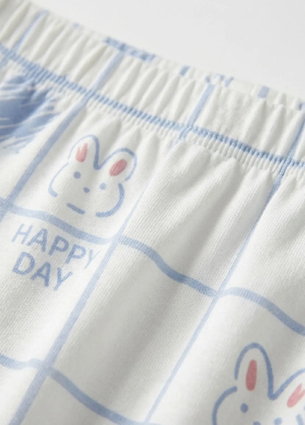 Textile with cartoon bunny faces and 'Happy Day' text on a checkered pattern