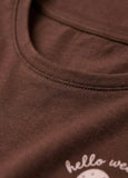 Close-up of a brown shirt with 'hello weekend' text on a white background